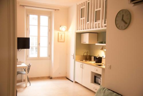 une cuisine avec des placards blancs et une horloge murale dans l'établissement ★ LE PETIT AVIGNONNAIS ★ COUNTRYSIDE ★ INTRAMUROS ★ CENTER ★, à Avignon