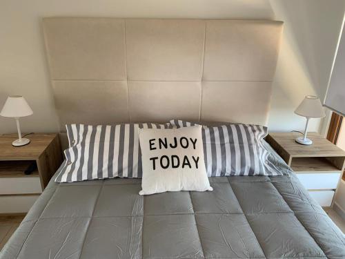 a bed with a pillow with the words enjoy today on it at B TWINS - Vacaciones Soñadas a metros del Mar in Pinamar