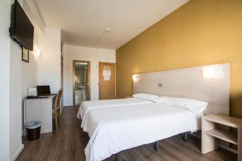 a bedroom with a large white bed and a television at Hotel Benidorm City Olympia in Benidorm