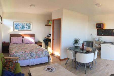 ein Schlafzimmer mit einem Bett und einem Tisch sowie eine Küche in der Unterkunft Cabañas Suite Matanzas in Navidad