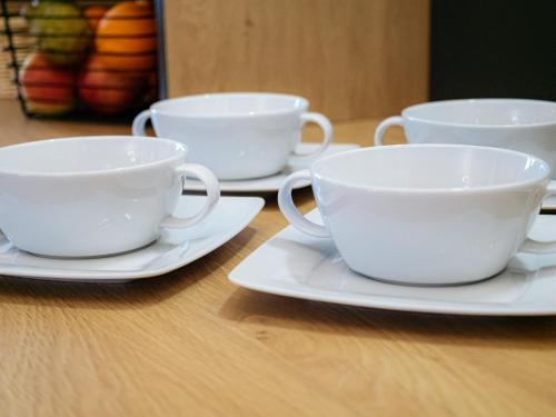 three white cups and saucers on a table at Rezydencja Markowy Dworek in Białka Tatrzanska