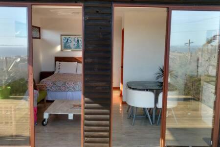 ein Zimmer mit einem Tisch und ein Schlafzimmer mit einem Bett in der Unterkunft Cabañas Suite Matanzas in Navidad