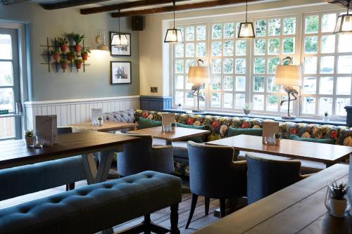 a restaurant with wooden tables and chairs and windows at Ravensworth Arms by Chef & Brewer Collection in Gateshead