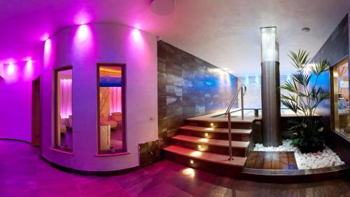 una camera con illuminazione viola e scala in un edificio di Hotel La Maison Wellness & Spa ad Alleghe