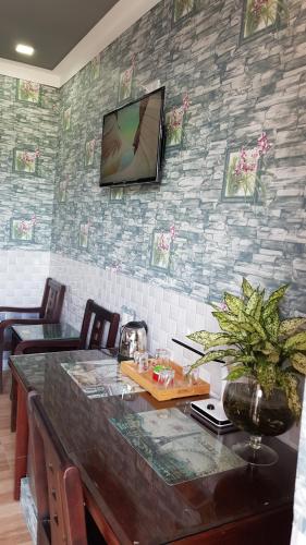 Zimmer mit einem Tisch und einem TV an der Wand in der Unterkunft Khách sạn Ánh Đông in Phan Rang