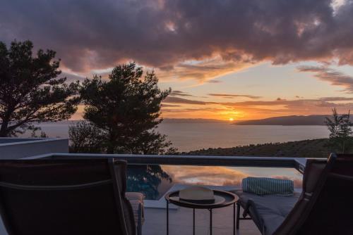a pool with a table and chairs and a sunset at Villa Kuk with heated salt water pool - Makarska in Makarska