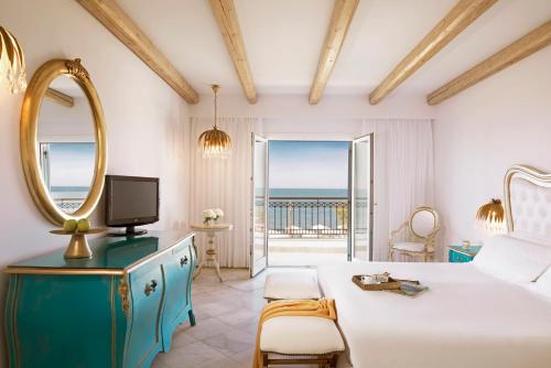 a bedroom with a bed and a mirror and a television at Mitsis Selection Laguna in Hersonissos