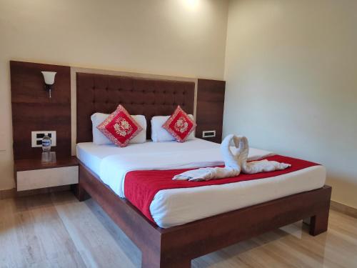 a bedroom with a large bed with red and white pillows at Hotel Grand Ganesha in Ganpatipule