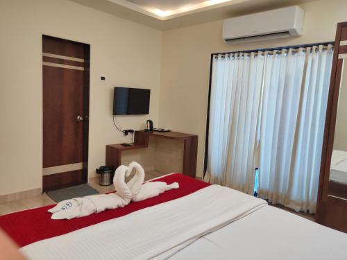 a bedroom with a bed with two towels on it at Hotel Grand Ganesha in Ganpatipule