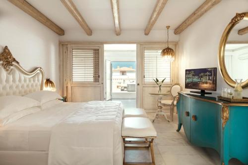 a bedroom with a large white bed and a mirror at Mitsis Selection Laguna in Hersonissos