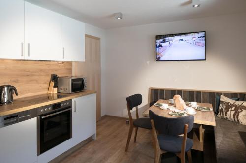 eine Küche und ein Esszimmer mit einem Tisch und einem TV an der Wand in der Unterkunft Apart Jöchler in Tux