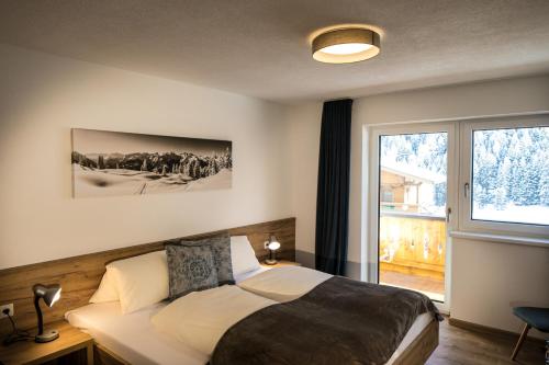 ein Schlafzimmer mit einem Bett und einem großen Fenster in der Unterkunft Apart Jöchler in Tux