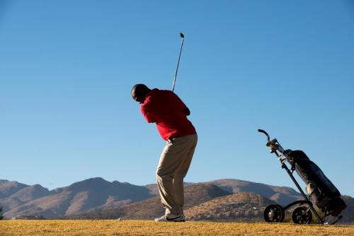 Un uomo in piedi sulla cima di una collina con un telescopio di Windhoek Country Club Resort a Windhoek