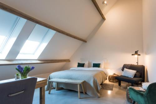 a attic bedroom with a bed and a chair at Hof Olmenstein in Goes