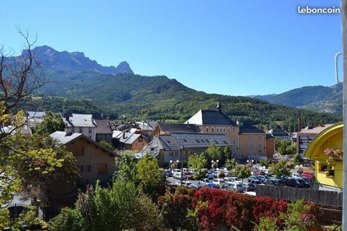 a town with a parking lot with mountains in the background at L étoile du verger in Barcelonnette