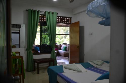 a bedroom with two beds and a window with green curtains at Green Woods in Kandy