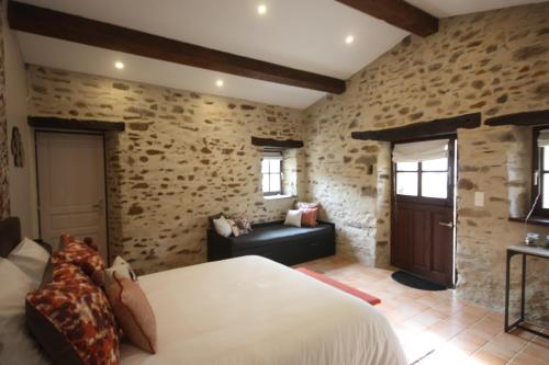 ein Schlafzimmer mit einem Bett und einer Couch in einem Zimmer in der Unterkunft Le Nichoir in Les Essarts
