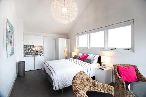 een slaapkamer met een bed en 2 stoelen en een kroonluchter bij Studio Sunrise in Zandvoort