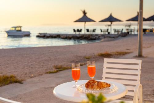 a table with two glasses of orange juice and bread on the beach at Apartments Antonio - Podstrana, Split in Podstrana
