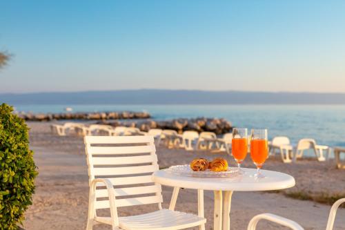 a table with two glasses of orange juice and some chairs at Apartments Antonio - Podstrana, Split in Podstrana