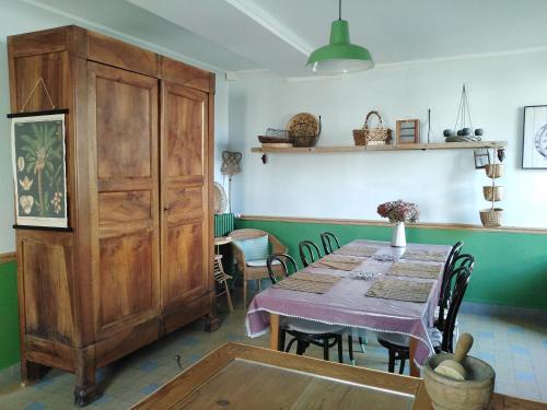 a dining room with a table and a large wooden cabinet at Meublé de tourisme La Maison d'Orgy in Chevannes