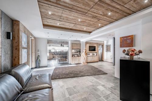 a living room with a leather couch and a kitchen at Hotel Regina in Obergurgl