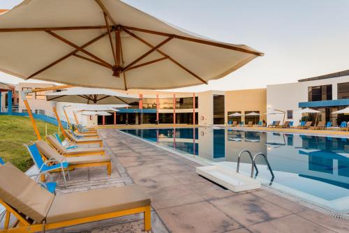 a pool with chairs and umbrellas next to a swimming pool at DM Hoteles Arequipa in Arequipa