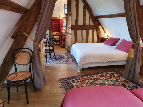 Saint-Pierre-AzifにあるB&B - Le Clos aux Masquesのベッド2台、テーブル、椅子が備わる客室です。
