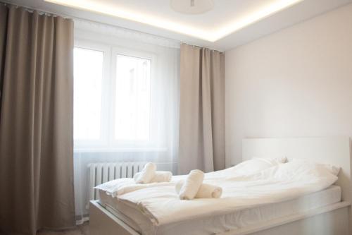 Un dormitorio blanco con una cama con dos ositos de peluche. en Apartament Karolewska, en Łódź