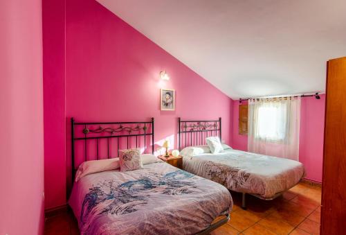 Duas camas num quarto com paredes cor-de-rosa em Casa Rural Las 6 Hermanas em São Martinho de Trevelho