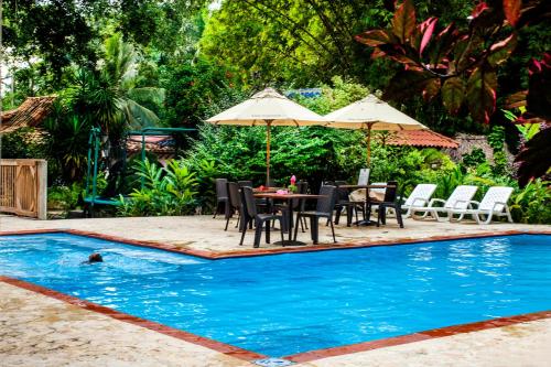 a pool with a table and chairs and an umbrella at Hotel Restaurante Selva Negra in Turbaco