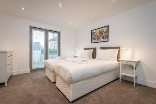 a white bedroom with a large bed and a window at Luxury Apartment with Garden, and Putting Green in St. Andrews