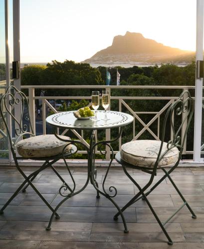 a table and two chairs with wine glasses on a balcony at dk villas 1 Harbour View Hout Bay in Hout Bay