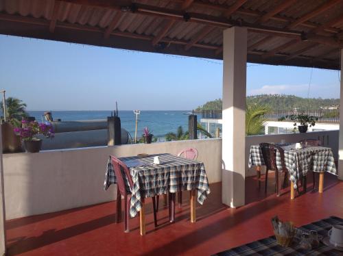 een patio met tafels en stoelen en uitzicht op de oceaan bij Sun Ocean Inn Mirissa in Mirissa