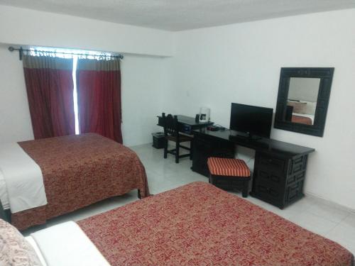 a hotel room with two beds and a desk and a mirror at Hotel Maya Tabasco in Villahermosa