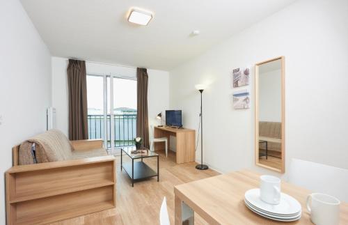 a living room with a table and a mirror at Ténéo Apparthotel Talence - Centre in Talence