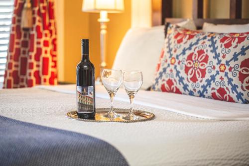 a bottle of wine and two wine glasses on a bed at The Marshall House, Historic Inns of Savannah Collection in Savannah