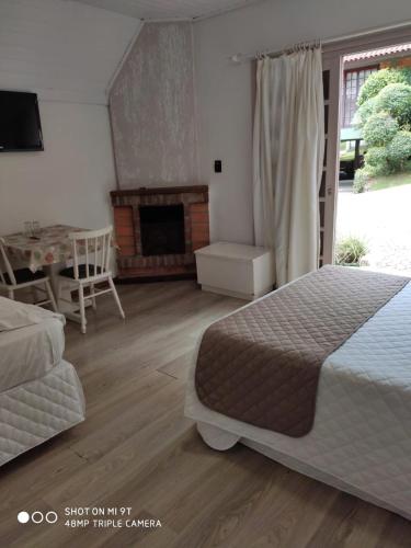 a bedroom with a large bed and a fireplace at Hotel Cabana Jardim de Flores in Gramado