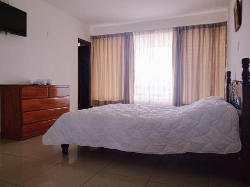 a bedroom with a bed and a dresser and a window at HOTEL TERRAZAS BOUTIQUE in Los Yoses