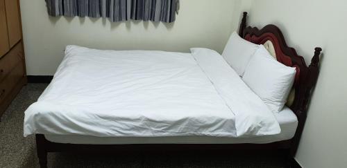 a bed with white sheets and pillows on it at Lanzhou 4th St in Chiayi City