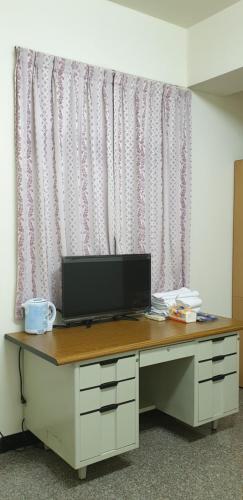 a desk with a television on top of it in front of a curtain at Lanzhou 4th St in Chiayi City