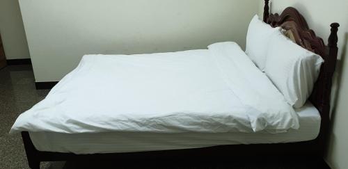 a bed with white sheets and pillows on it at Lanzhou 4th St in Chiayi City