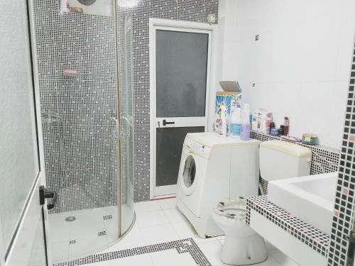y baño con lavadora y ducha. en Angie's Shared Villa TAM, en Tirana