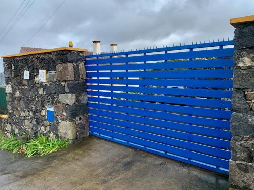 a blue fence next to a stone wall at Casa Varanda do Mar in Capelas