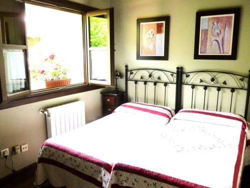 um quarto com uma cama branca e 2 janelas em Las endrinas em Llanes