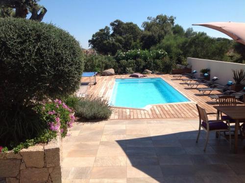 - une piscine avec des chaises, une table et un parasol dans l'établissement Villa RIVIERA, à Porto-Vecchio