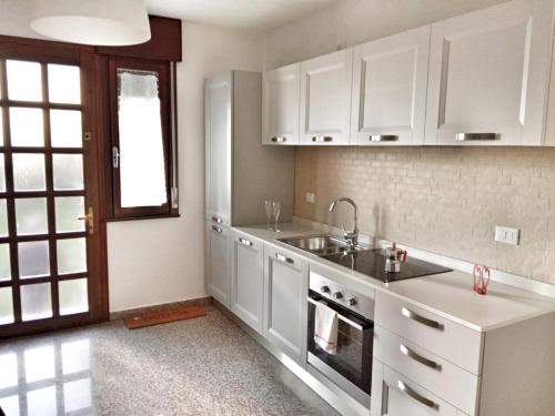 a kitchen with white cabinets and a sink at Red Tower Venice Apartment - 2 mins from VCE Airport- free Wifi in Tessera