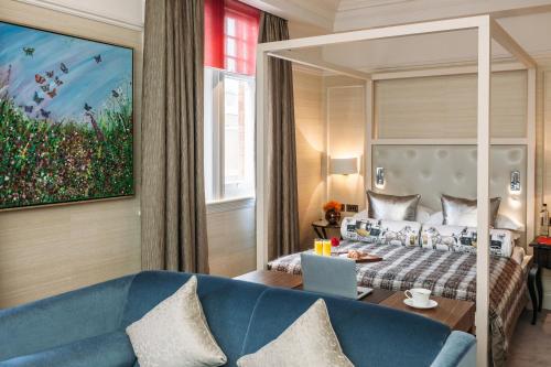 a hotel room with a bed and a blue couch at 11 Cadogan Gardens, The Apartments and The Chelsea Townhouse by Iconic Luxury Hotels in London