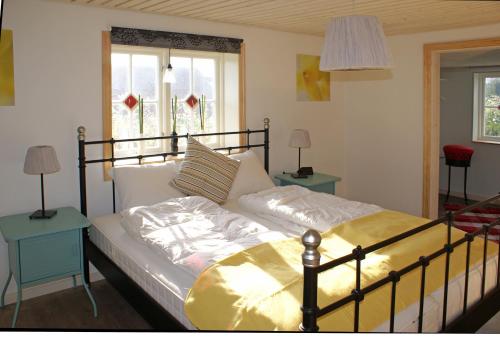 Bett in einem Zimmer mit 2 Tischen und 2 Fenstern in der Unterkunft Haus Fjäril in Laxeby