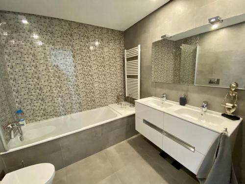 Un baño con dos lavabos, una bañera y un inodoro. en SeaHorse House, en Esposende